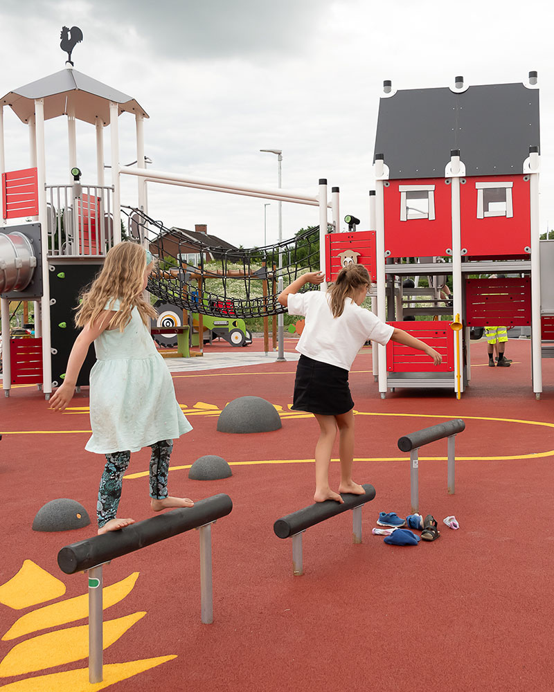 Girls are walking across balance beams on a playground.